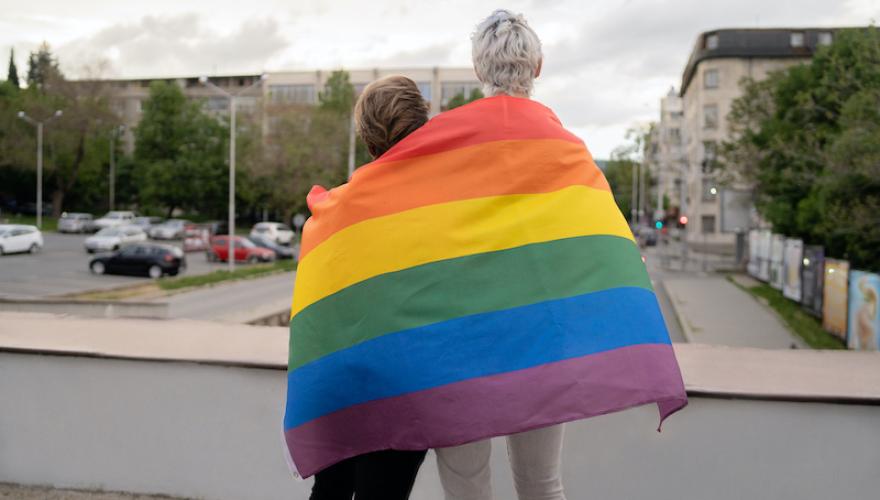 PRIDE FLAG ON THE BACKS OF 2 PEOPLE