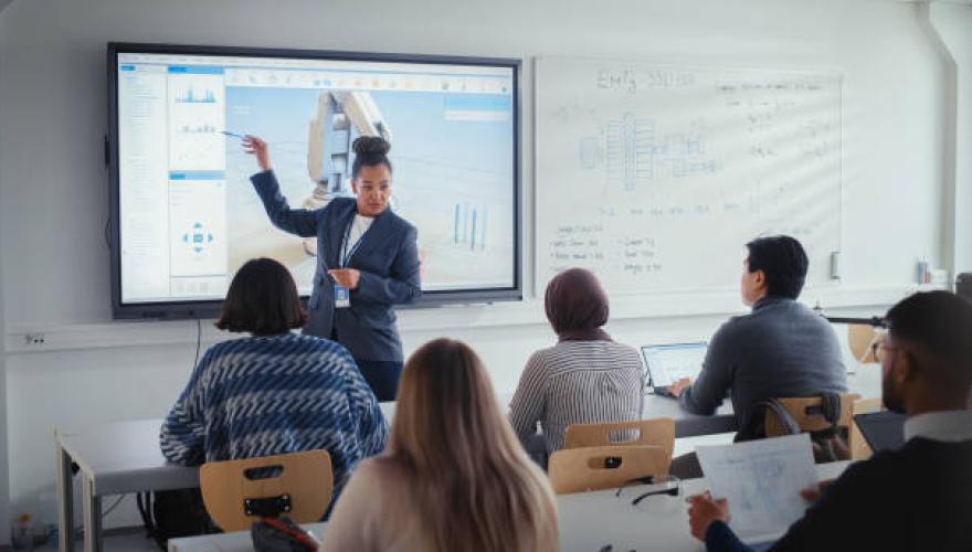FEMALE TEACHER AT WHITEBOARD IN CLASSROOM