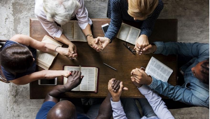 group around table, holding hands, bible study