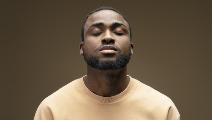 Young man meditating with closed eyes and neutral expression