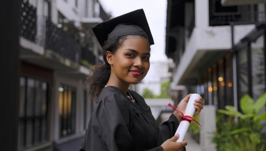 FEMALE GRADUATE IN GOWN WITH DIPLOMA
