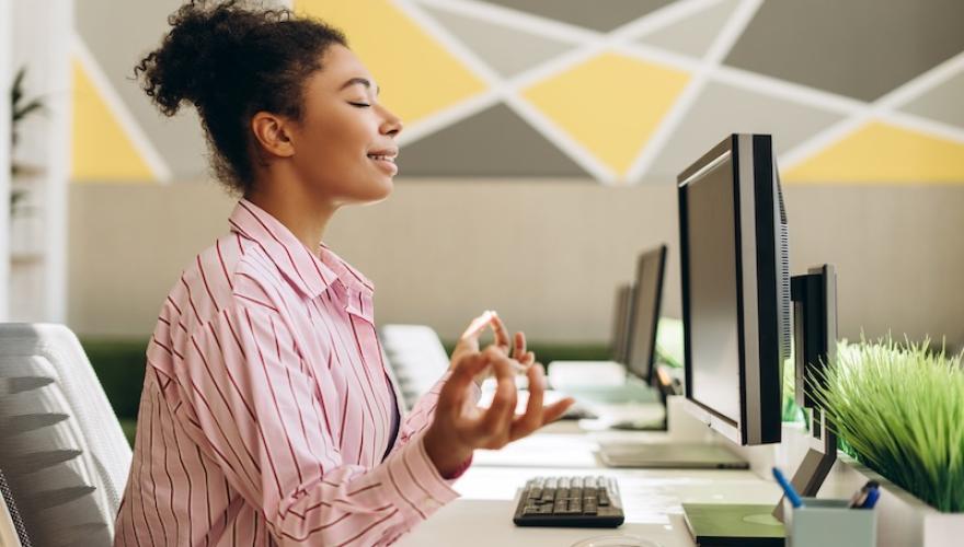 WOMAN MEDITATING AT WORK DESK