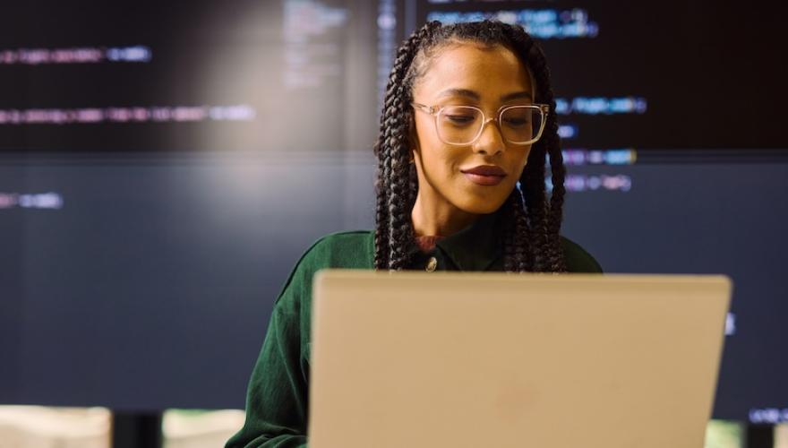 women at laptop, tech language background