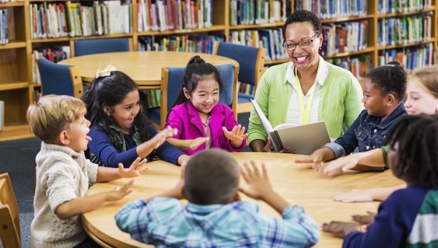 female teacher reading to students in library