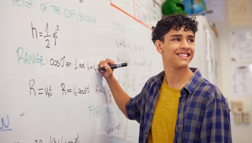 teen writes on whiteboard in classroom