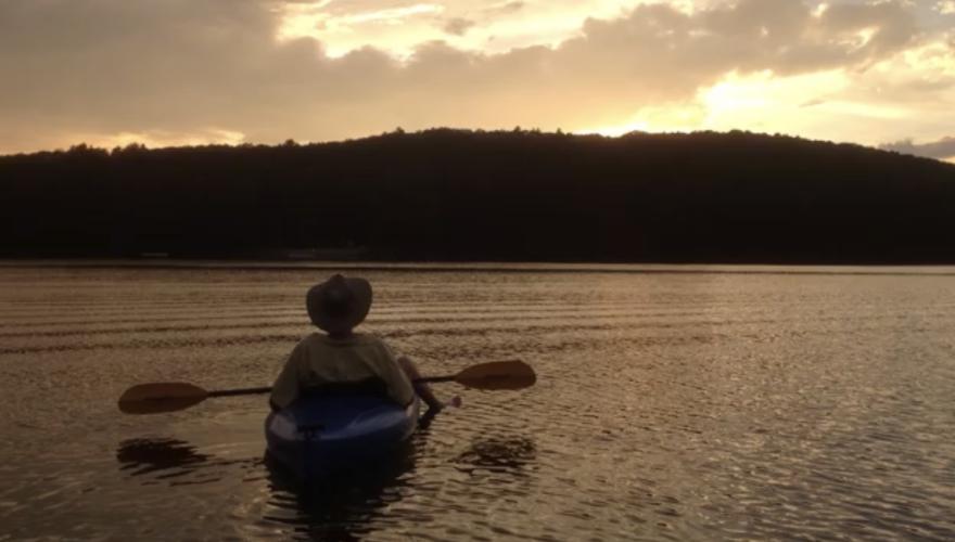 Image of a person in a small boat holding oars overlooking an ocean