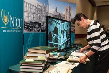 Visitor reviewing display of past NJCU documents and books during Alumni Weekend