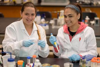 two female biology students experimenting in lab