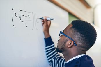 male math student working out equations on whiteboard