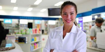 Pharmacy technician in front of shelves of medicine