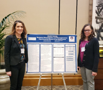 TWO WOMEN IN FRONT OF PRESENTATION BOARD