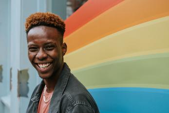 Person smiling in front of Pride Flag