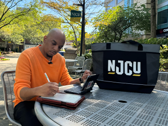 Individual studying outside on the campus of NJCU.